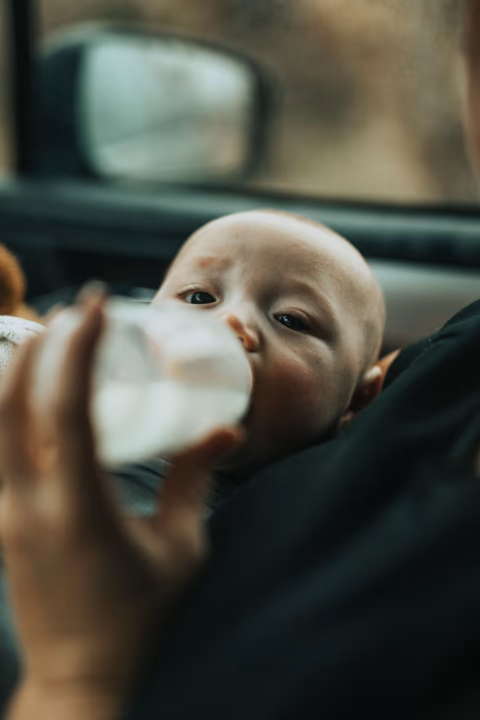 A caregiver bottle-feeding a baby